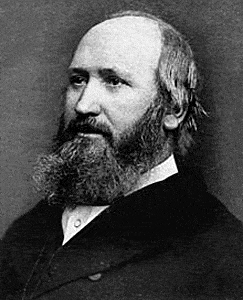 Headshot of a man with a full beard and thinning hair. He has a thick neck and soldi build. He is dressed in a dark suit, white shirt and bowtie.